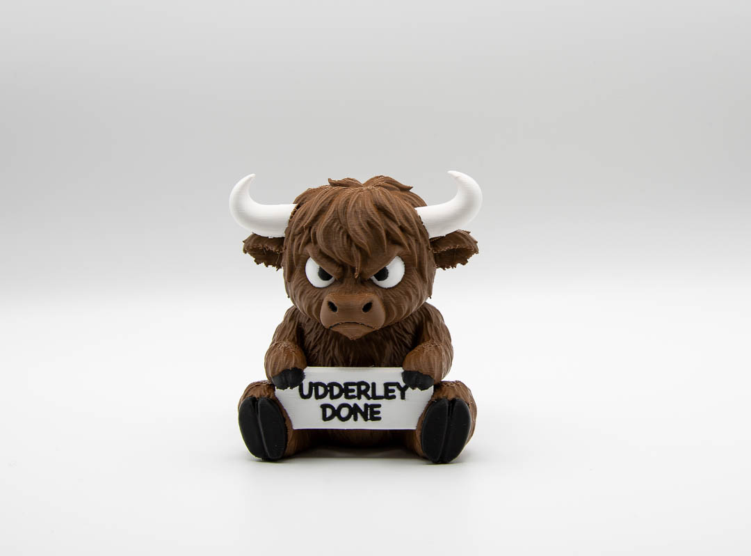 Grumpy 3D printed Highland cow holding an Udderly Done sign, front view