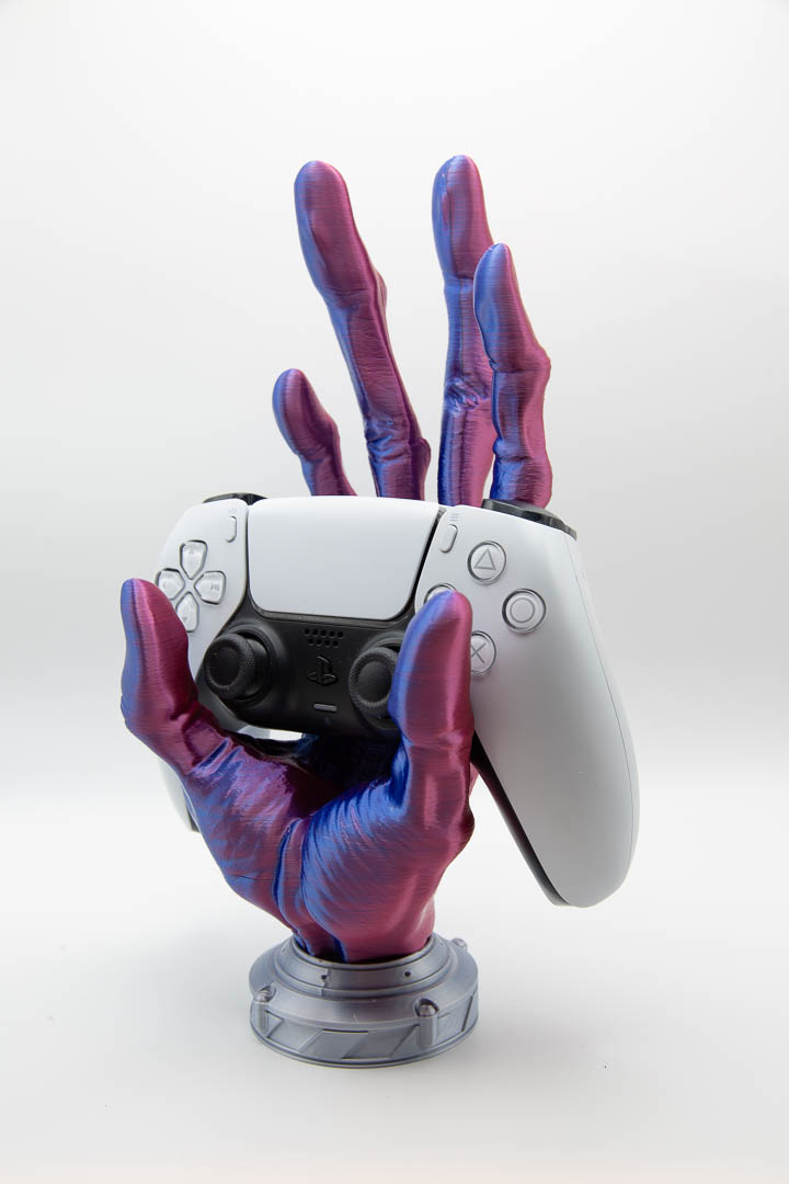 Alien hand controller holder holding a PS5 DualSense controller