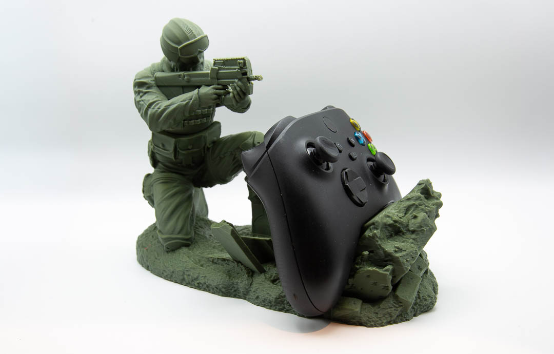 Green soldier controller holder with an Xbox controller resting behind the wall